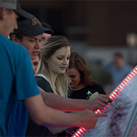 Image of attendees writing on an art piece.