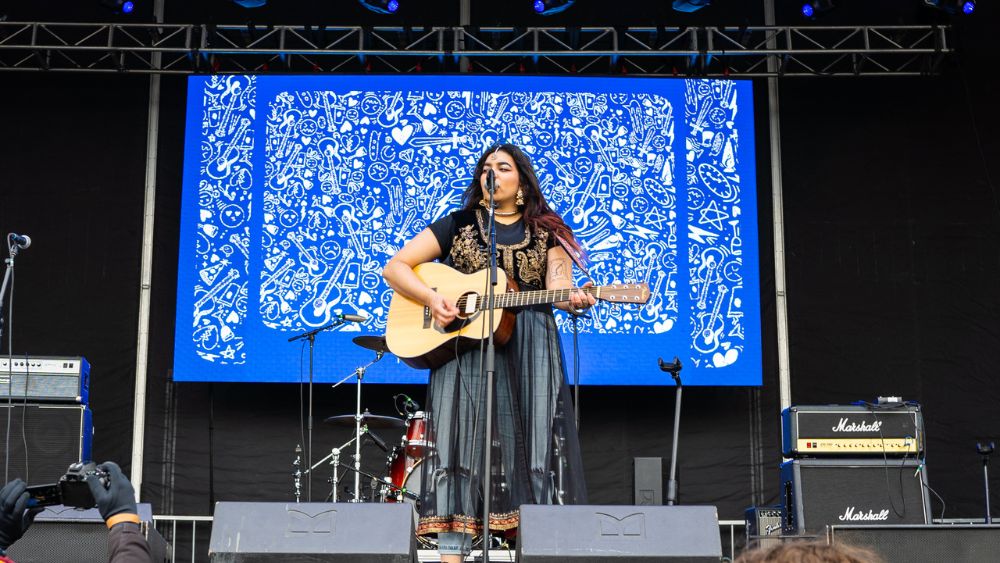 Performer singing and playing guitar onstage