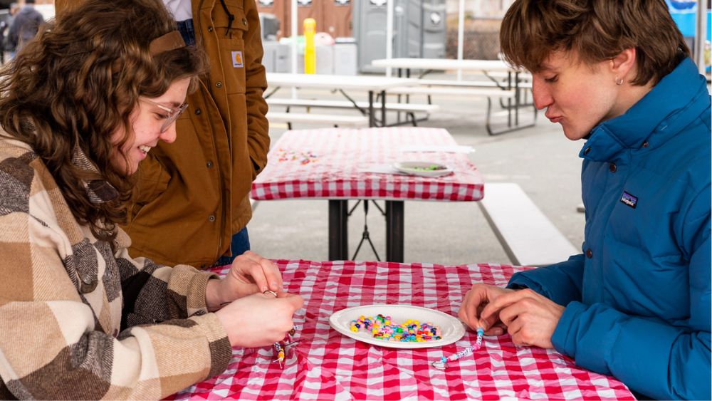 Students making beaded bracelets at a table
