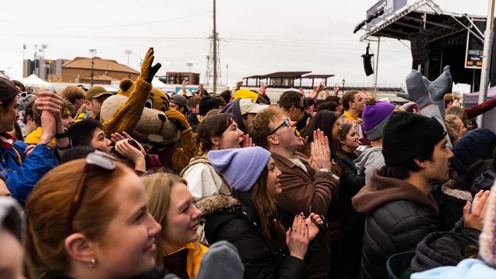 Goldy and students jumping in a concert crowd