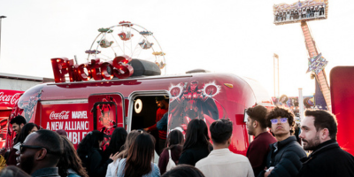 Line of students at a trailer branded with Marvel and Coca Cola logos.