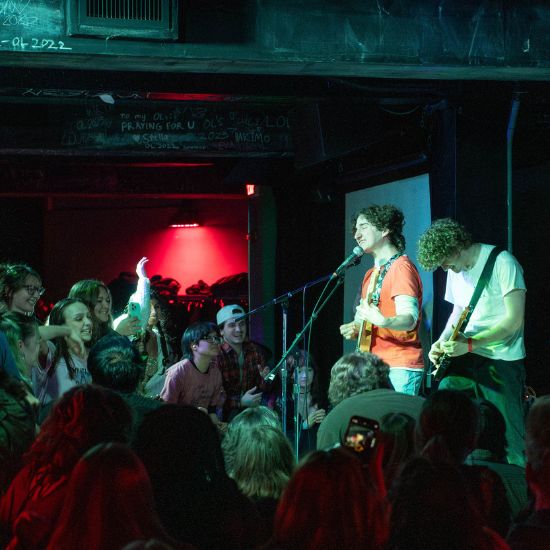 Musicians performing on a small stage with an enthusiastic audience.